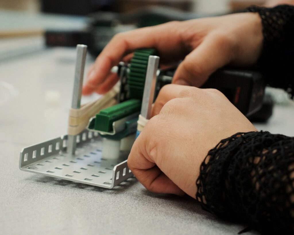 person in black and white long sleeve shirt using white and green braille machine